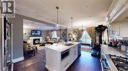 Kitchen with open floor plan, decorative light fixtures, white cabinets, stainless steel appliances, and crown molding - 