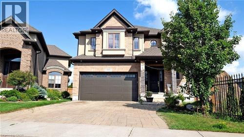 View of front of property with decorative driveway, an attached garage, a shingled roof, and brick siding - 537 Millstream Drive, Waterloo, ON - Outdoor With Facade