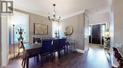 Dining room featuring crown molding, a chandelier, and dark wood finished floors - 