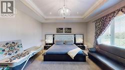 Carpeted bedroom featuring crown molding, a raised ceiling, and a chandelier - 