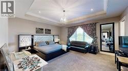 Carpeted bedroom featuring a tray ceiling, a chandelier, and ornamental molding - 