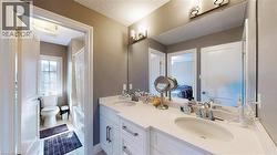 Ensuite bathroom with double vanity, shower / tub combo with curtain, and light tile patterned floors - 