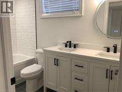 Full bathroom featuring double vanity, shower / bath combination, and dark tile patterned flooring - 