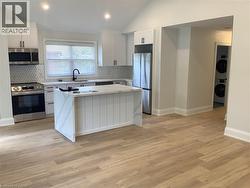 Kitchen with a center island, stainless steel appliances, white cabinets, light stone countertops, and backsplash - 