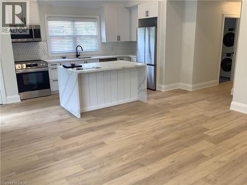 Kitchen with a center island, stainless steel appliances, white cabinets, light stone counters, and light wood finished floors - 229 West 18Th Street, Hamilton, ON - Indoor Photo Showing Kitchen With Stainless Steel Kitchen With Upgraded Kitchen
