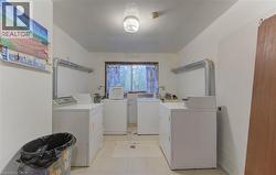 Shared laundry room featuring separate washer and dryer and light tile patterned floors - 