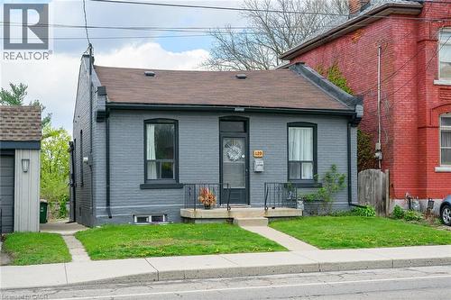 View of front of house with a shingled roof, brick siding, a front yard, and a chimney - 129 Dundurn Street N, Hamilton, ON - Outdoor