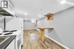 Kitchen featuring white appliances, white cabinets, light wood finished floors, baseboards, and dark countertops - 