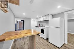 Kitchen with white appliances, light wood-style floors, white cabinets, recessed lighting, and a sink - 