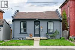 View of front facade featuring brick siding, a shingled roof, a front yard, and a gate - 