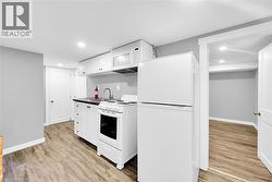 Kitchen with white appliances, light wood finished floors, white cabinetry, and recessed lighting - 