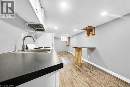 Kitchen featuring a sink, white cabinets, light wood-style flooring, baseboards, and recessed lighting - 129 Dundurn Street N, Hamilton, ON - Indoor
