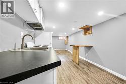 Kitchen featuring a sink, white cabinets, light wood-style flooring, baseboards, and recessed lighting - 