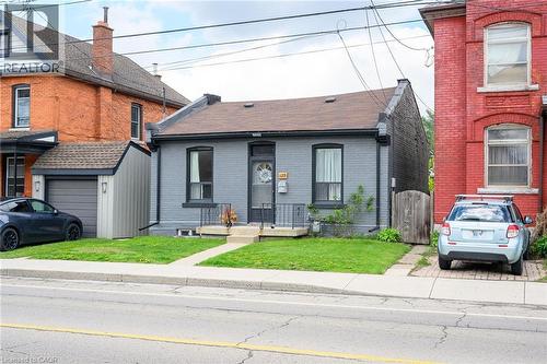 View of front of house featuring brick siding, a gate, a garage, a front lawn, and roof with shingles - 129 Dundurn Street N, Hamilton, ON - Outdoor