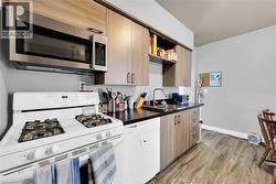 Kitchen with white appliances, a sink, light wood-style floors, dark countertops, and open shelves - 