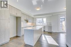 Kitchen with dark wood-style flooring, light stone countertops, modern cabinets, decorative backsplash, and recessed lighting - 