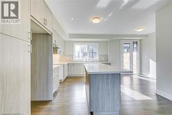 Kitchen featuring light wood-type flooring, backsplash, a kitchen island, under cabinet range hood, and recessed lighting - 