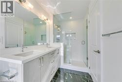 Bathroom featuring a shower stall, double vanity, and dark marble finish flooring - 