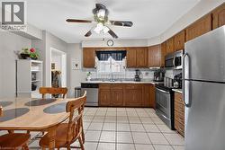 Kitchen featuring stainless steel appliances, light countertops, backsplash, light tile patterned floors, and a ceiling fan - 