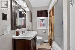 Bathroom with vanity, shower / bath combo with shower curtain, and light tile patterned floors - 