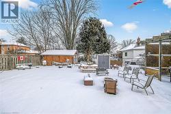 Yard layered in snow with a storage unit and a fenced backyard - 