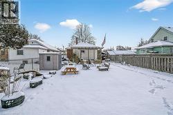 Yard layered in snow featuring a fenced backyard, a residential view, and a storage shed - 