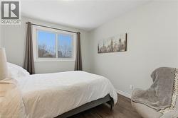 Bedroom featuring dark wood finished floors and baseboards - 