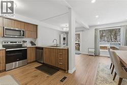 Kitchen with appliances with stainless steel finishes, modern cabinets, a peninsula, hanging light fixtures, and light wood-style flooring - 