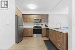 Kitchen with stainless steel appliances, modern cabinets, light wood finished floors, light stone counters, and decorative backsplash - 