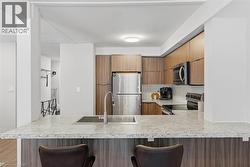 Kitchen with a breakfast bar area, stainless steel appliances, modern cabinets, brown cabinets, and a peninsula - 