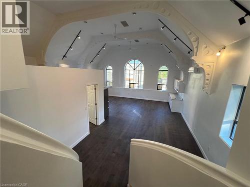Corridor featuring rail lighting, dark wood-type flooring, and lofted ceiling - 612 Upper James Street, Hamilton, ON 