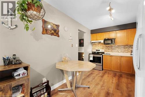 Kitchen featuring light countertops, backsplash, stainless steel electric range oven, light wood-style flooring, and black microwave - 75 Marisa Street, Kitchener, ON - Indoor Photo Showing Other Room