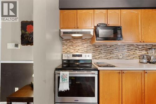 Kitchen featuring stainless steel range with electric stovetop, light countertops, black microwave, under cabinet range hood, and tasteful backsplash - 75 Marisa Street, Kitchener, ON - Indoor Photo Showing Kitchen