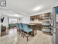 Kitchen featuring appliances with stainless steel finishes, a kitchen bar, a center island, light tile patterned floors, and dark brown cabinetry - 