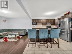 Kitchen featuring appliances with stainless steel finishes, a kitchen breakfast bar, a textured ceiling, dark brown cabinetry, and a kitchen island - 