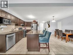 Kitchen featuring dark stone counters, a kitchen bar, appliances with stainless steel finishes, a kitchen island, and light tile patterned flooring - 