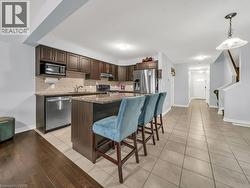 Kitchen featuring dark brown cabinetry, dark stone counters, a kitchen breakfast bar, a center island, and appliances with stainless steel finishes - 