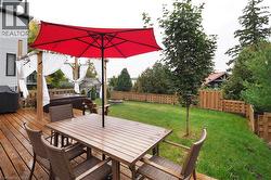 Deck featuring a fenced backyard, outdoor dining space, a hot tub, and a grill - 