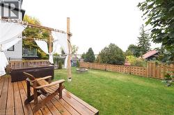 Fenced backyard with a hot tub, a wooden deck, and a fire pit - 