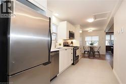 Kitchen with appliances with stainless steel finishes, white cabinetry, plenty of natural light, and tasteful backsplash - 