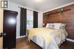 Bedroom featuring crown molding, dark wood-type flooring, and wooden walls - 