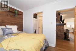 Bedroom featuring estacked washer and dryer, ornamental molding, and dark wood-type flooring - 