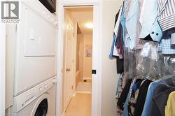 Laundry area featuring stacked washer / dryer and light tile patterned flooring - 