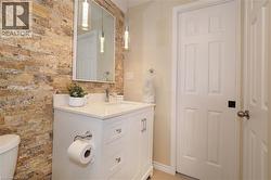 Half bathroom with vanity and brick wall - 