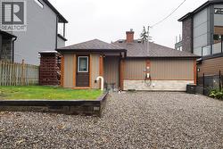 Back of house featuring a shingled roof, stone siding, board and batten siding, and a chimney - 