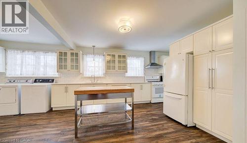 Kitchen with white appliances, wall chimney exhaust hood, glass insert cabinets, dark wood-style flooring, and beam ceiling - 14 Grandview Street, Brantford, ON - Indoor Photo Showing Laundry Room