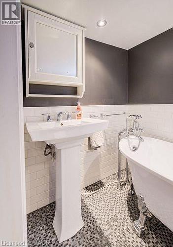 Bathroom featuring a freestanding tub, a wainscoted wall, tile walls, light tile patterned flooring, and recessed lighting - 14 Grandview Street, Brantford, ON - Indoor Photo Showing Bathroom