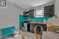 Kitchen featuring stainless steel range with electric stovetop, radiator, white microwave, under cabinet range hood, and light tile patterned flooring - 