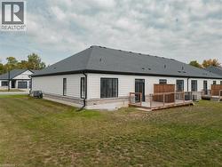 Back of house featuring a wooden deck, a lawn, brick siding, and roof with shingles - 