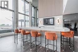 Kitchen featuring floor to ceiling windows, healthy amount of natural light, a kitchen breakfast bar, baseboard heating, and a high ceiling - 